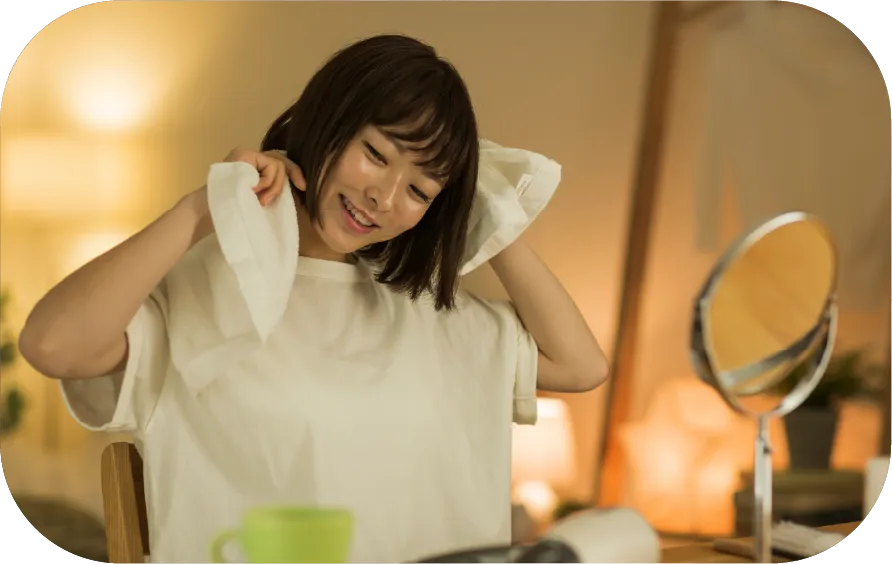 塗れた髪をタオルで乾かす女性のそばにマグカップ