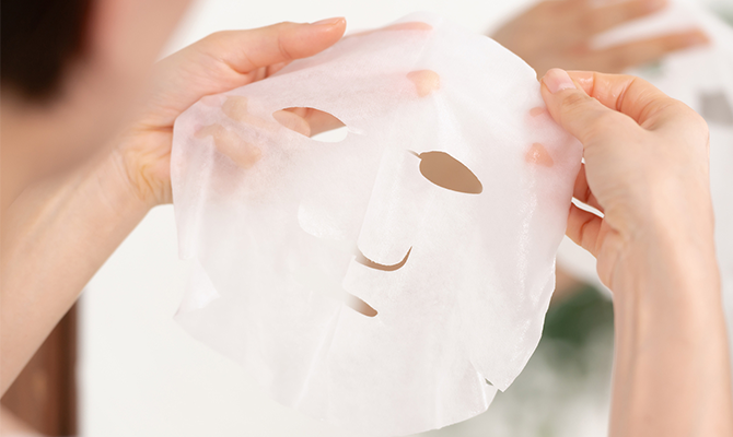 シートマスクを両手で広げる女性の画像