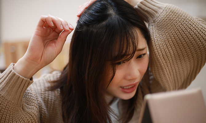 白髪を見つけて悲しい顔をする若い女性