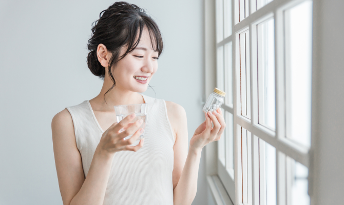 サプリメントの瓶を持つ女性