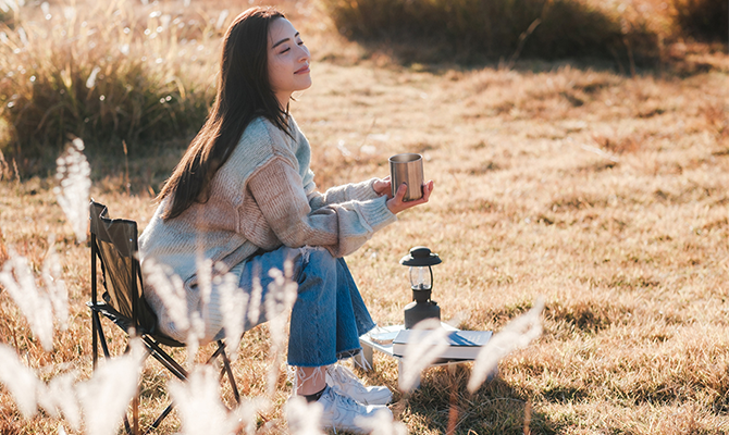 ソロキャンプ中に飲み物を飲む女性