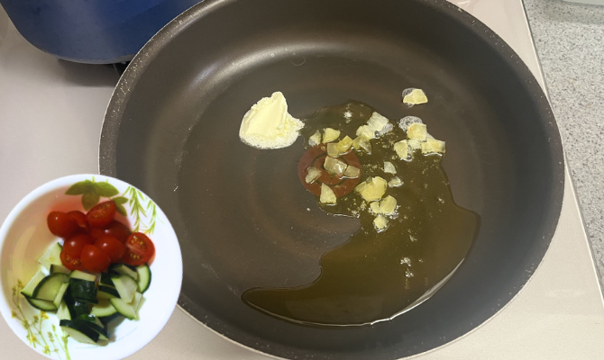 フライパンにオリーブオイル、バター、みじん切りにんにくを入れたフライパン／適当なサイズに切ったズッキーニとトマト