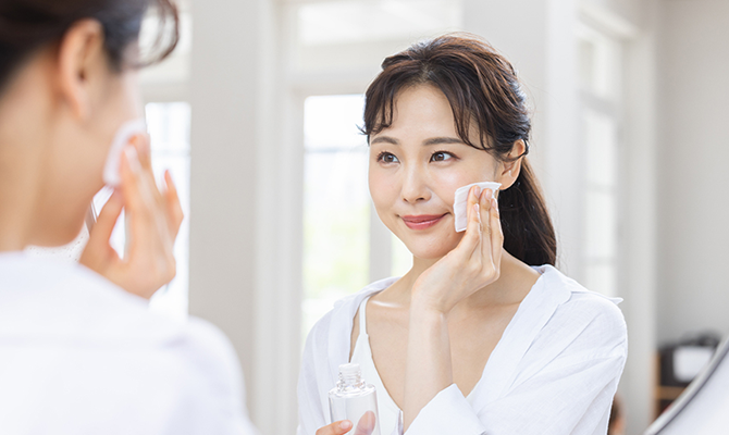 鏡に向かってスキンケアをする女性