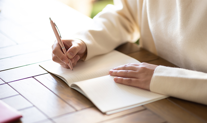 ノートに出来事や考えを書いている手