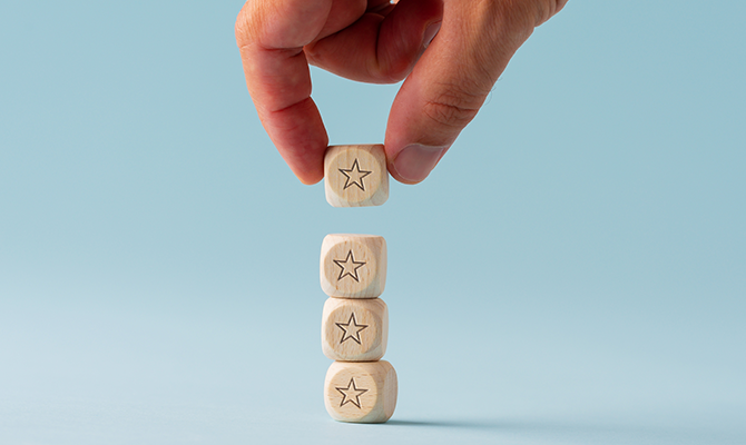 星が書かれた木製の積み木を4つ積み上げる手