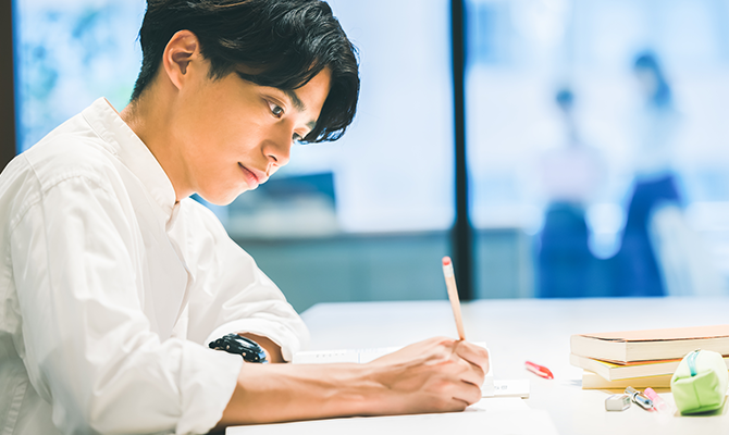 ノートにその日の出来事を書く男性