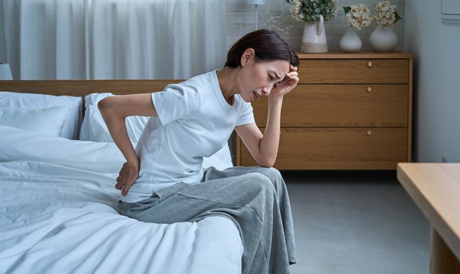 ベッドに腰掛け憂鬱そうな顔をしている女性